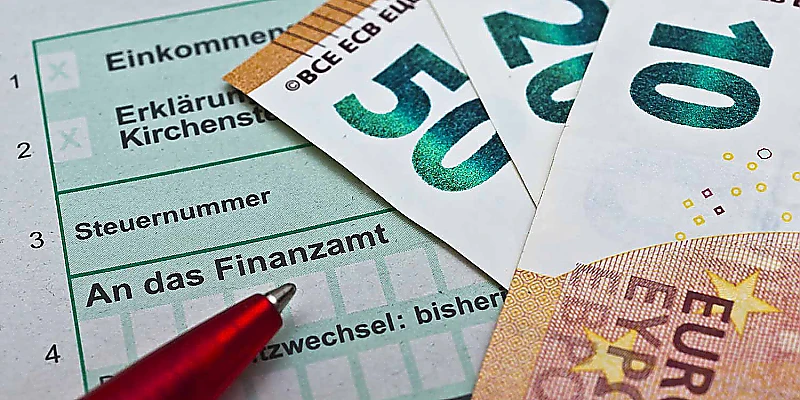 Einkommensteuer und Finanzamt mit Formular, Geldscheinen und Stift